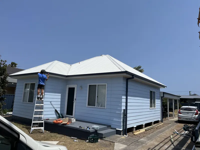 Weatherboard cottage with its new white metal roof